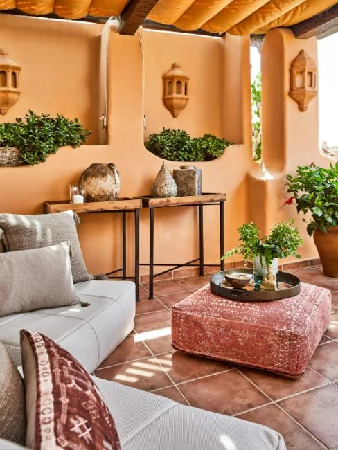 Inspiration aux murs terre cuite, canapé gris, pouf rouge et objets artisanaux.